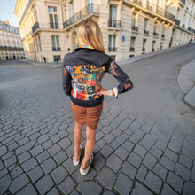 Load image into Gallery viewer, oohlala girls black denim jacket with vibrant back graphic print and lace sleeves worn by a woman on a city street
